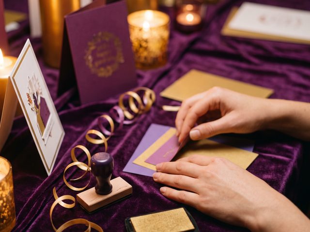 Hands assembling a handmade greeting card among cardstock and ribbon