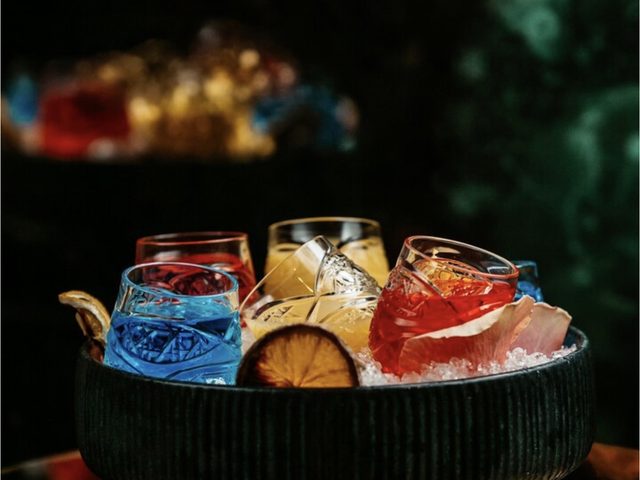 Cocktails in tumblers packed into a bowl of ice
