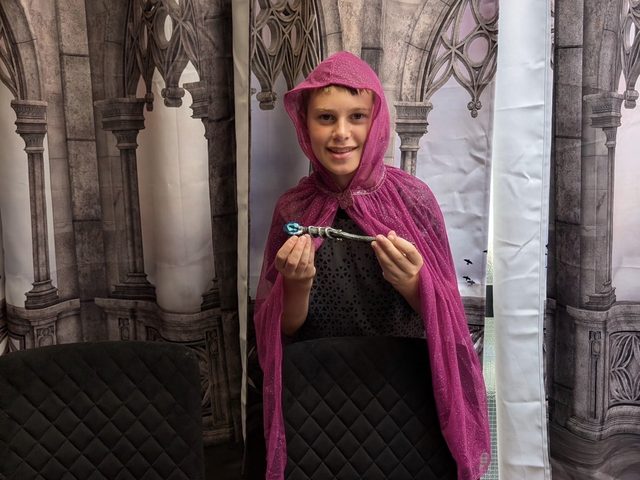 A child in a hooded magenta cloak in front of the cathedral backdrop