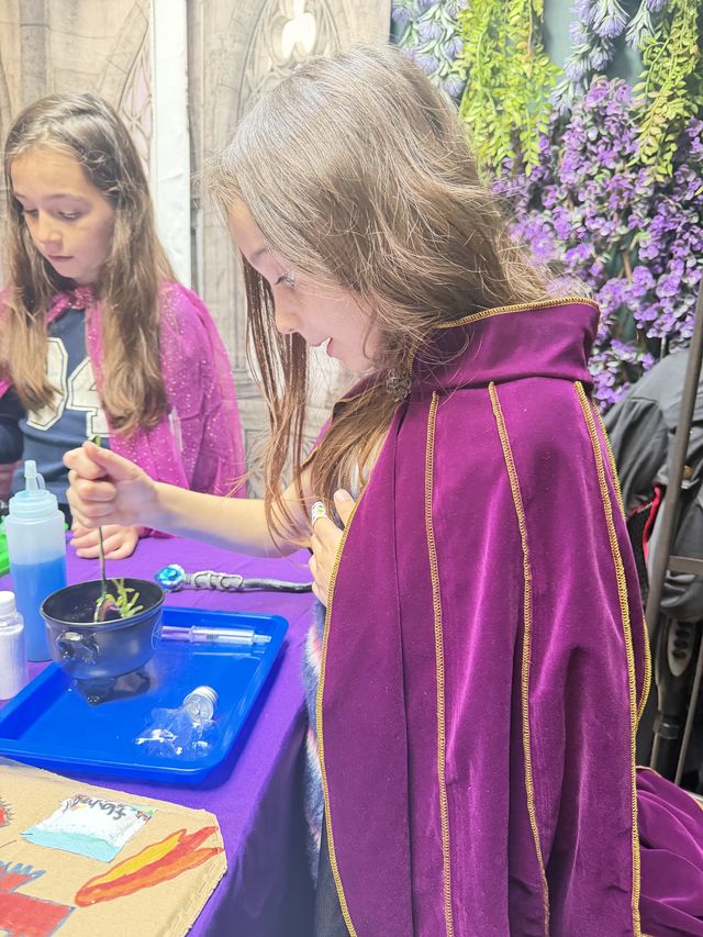 A girl in a purple cloak stirring her cauldron