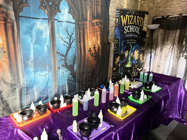 A potion table set up beneath a gothic window backdrop