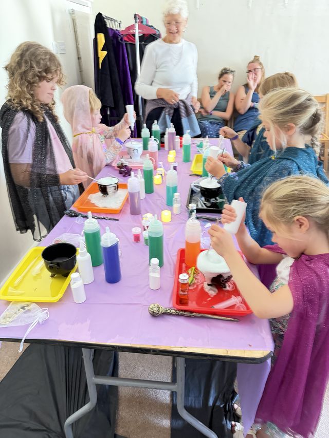 Children making potions in a hall while grown-ups watch