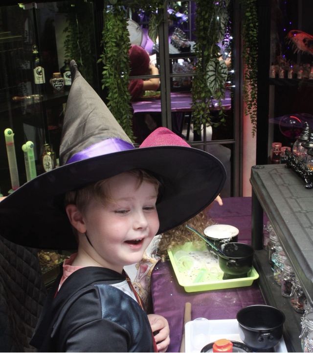 A boy in a wizard hat grinning at the camera