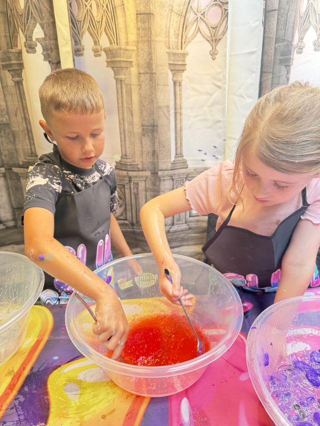 Two children mixing a bowl of red slime