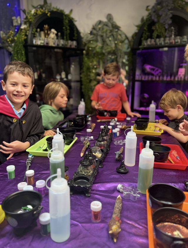 Children in robes making potions at the long table