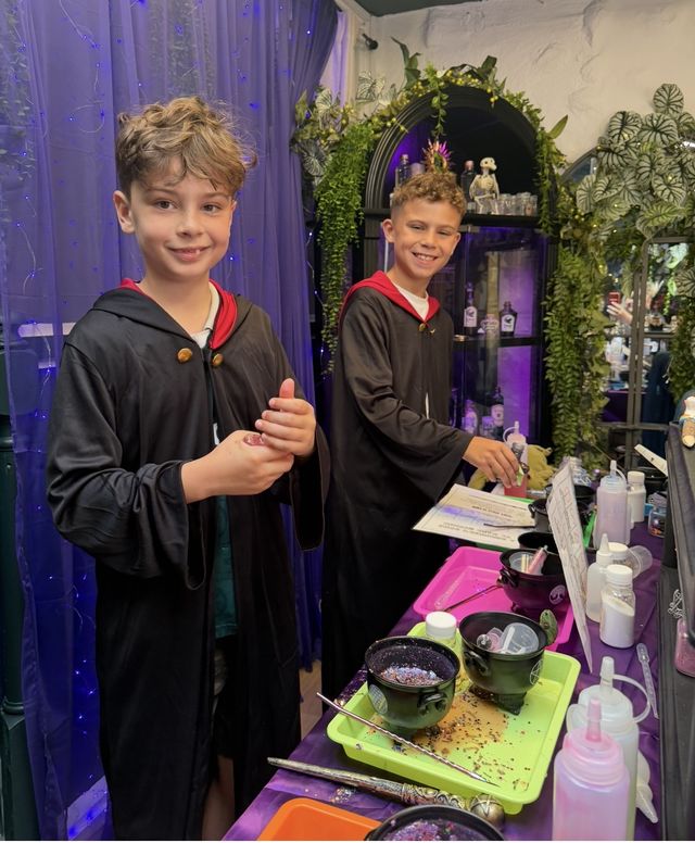 Two boys in wizard robes at the potion bench
