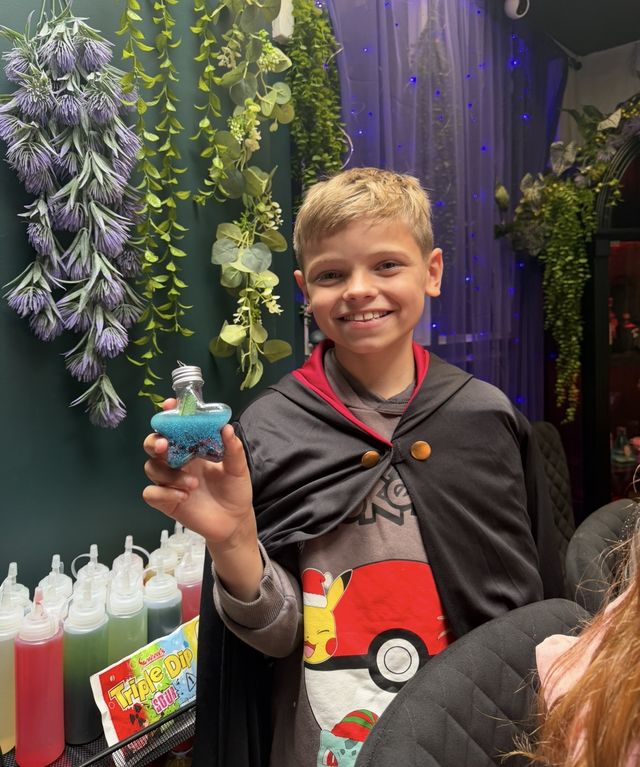 A boy holding up the potion bottle he made