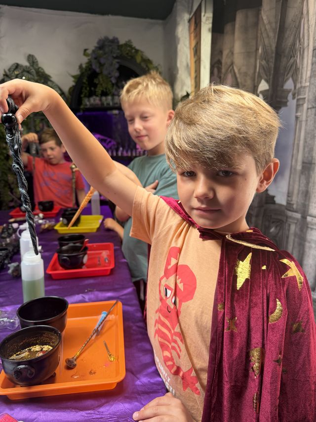 A boy in a star cape holding his wand up high