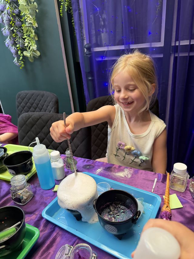 A girl holding up a cauldron of foaming potion