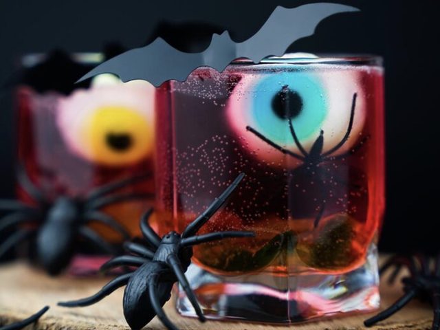 Halloween drinks with jelly eyeballs and plastic spiders on a log slice