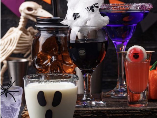 A Halloween table with skeleton props, a ghost drink and dark cocktails