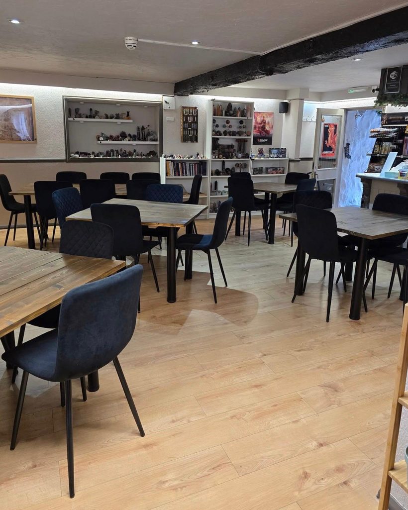 The Legends Lair: long handmade wooden tables and black chairs, shelves of crystals and fantasy artifacts along the walls