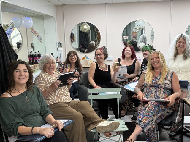 A life drawing group laughing together with sketchpads on their knees