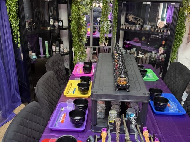 The potion bench set up with wands on a rack, cauldrons and apothecary shelves behind