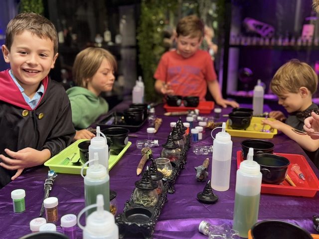 The potion table laid out with cauldrons, wands and coloured bottles before a party