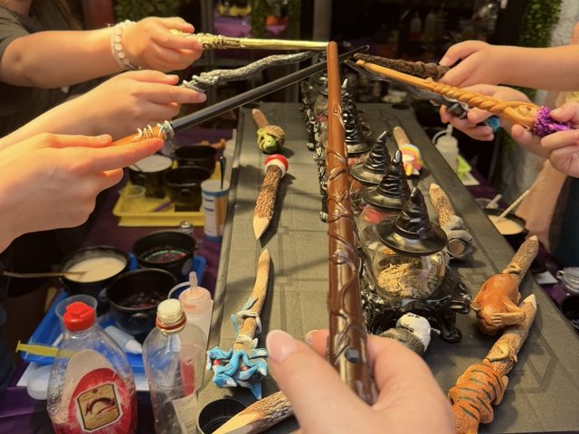 Children reaching in with wands over the potion table