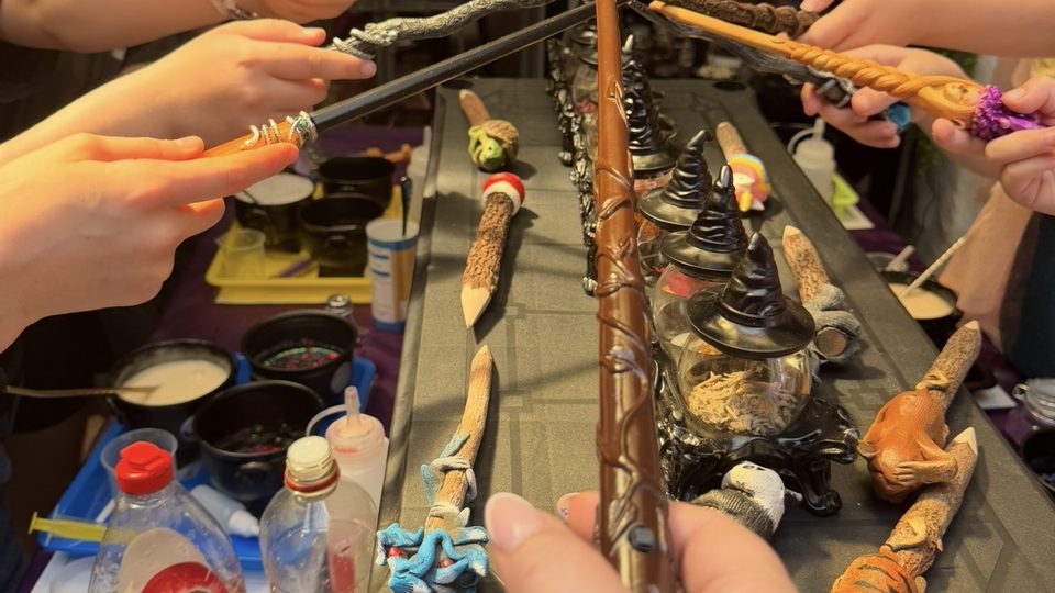 Children reaching in with wands over the potion table